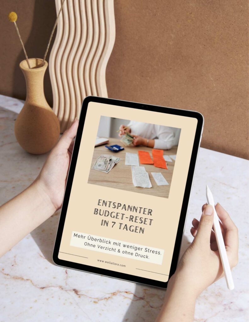 Workbook am Ipad zum Thema Entspannter Budget-Reset in 7 Tagen. Hintergrund Schreibtisch in Marmoroptik und Stil-Life in beigen Farben.